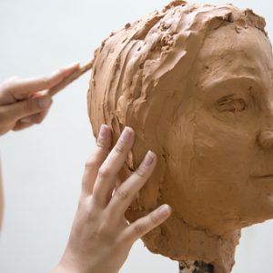 Artist working on clay sculpture in art studio